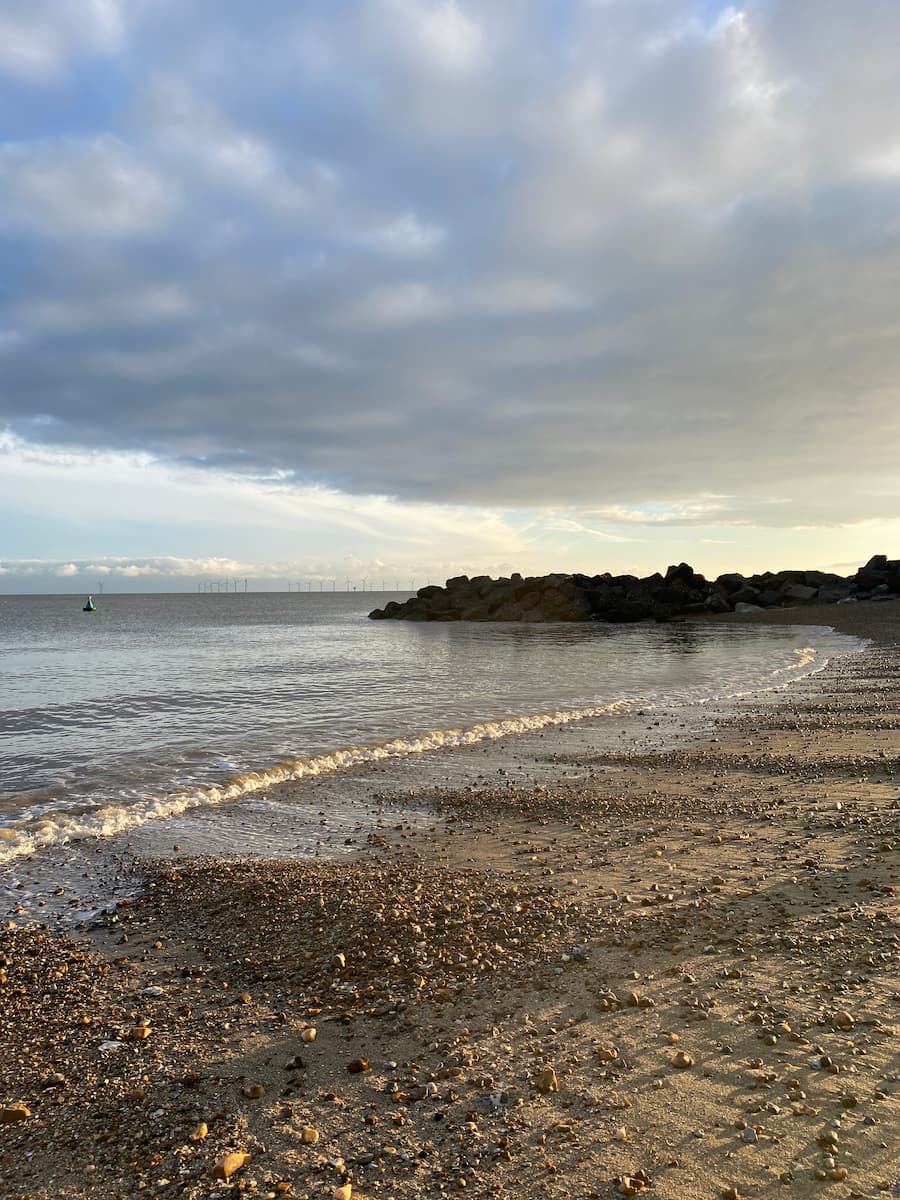 Essex coastline of sand and shingle beach enclosed by rocks in the background