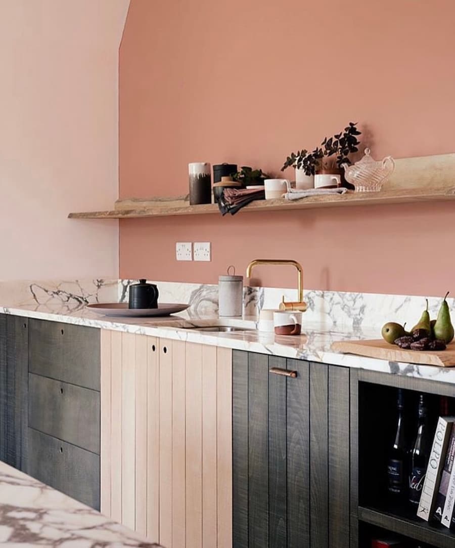 Kitchen with peach painted walls and base units made from timber of neutral wood and grey
