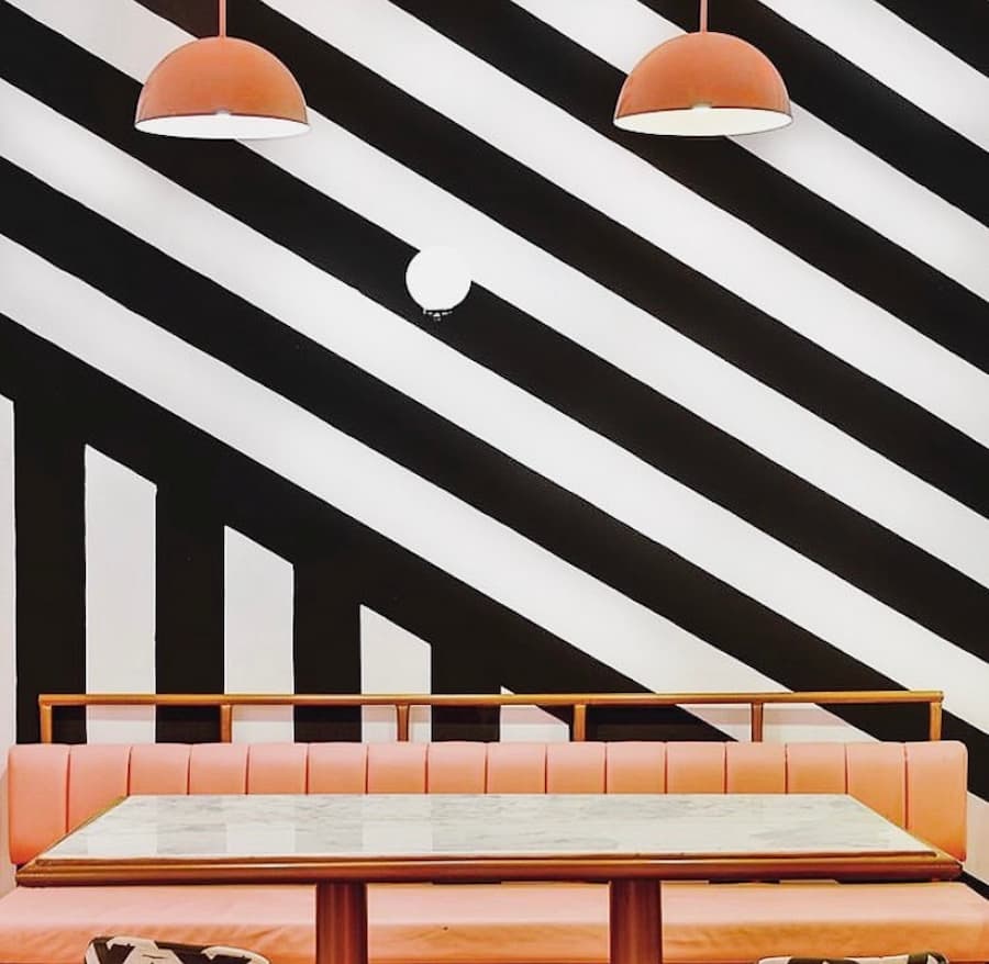 Bold monochrome colour blocked wall with peach seating and lighting