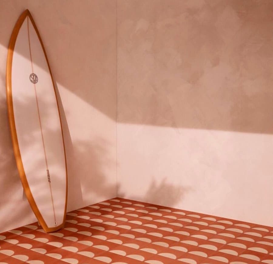 Peach Fuzz painted walls with peach fuzz and terracotta tiled floor and a peach fuzz surfboard propped up against the left wall