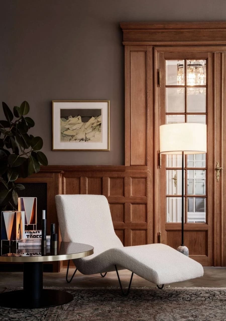 cream chaise lounge in front of a wooden panelled wall