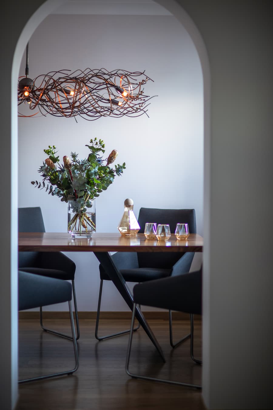 statement dining table through an archway with dramatic lighting positioned above
