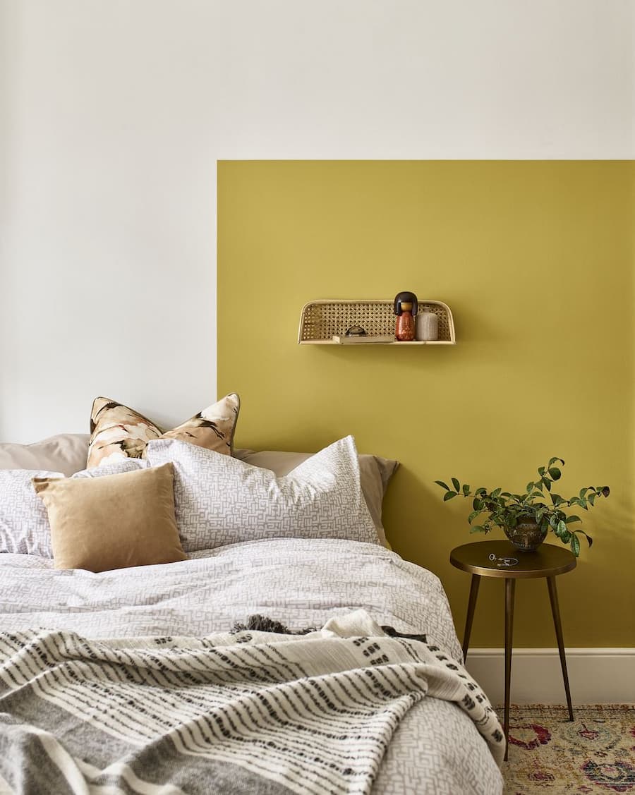 Mustard yellow colour blocking for a bedroom to add warmth to a stark white room