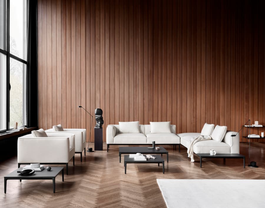 Large living room with dark wood panelled feature walls and a selection of cream sofas positioned in a u-shape