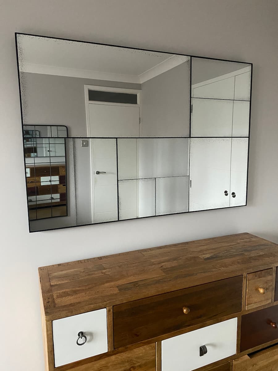 New sleek contemporary mirror positioned above the chest of drawers