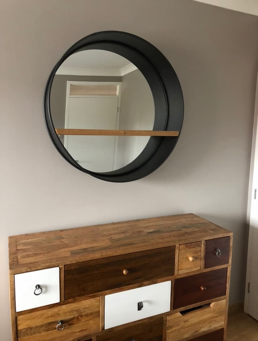 Original mirror before the transformation Large porthole mirror positioned above the chest of drawers