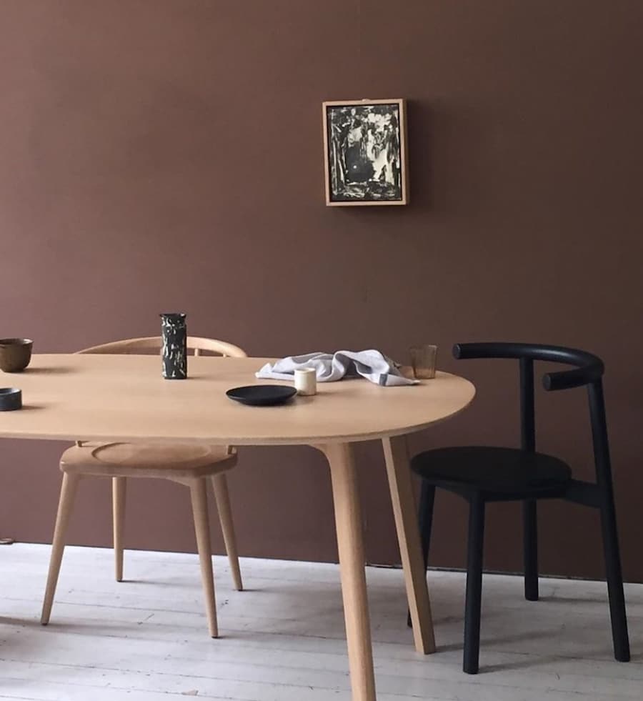 rich chocolate brown painted wall with dining table and chairs positioned in front