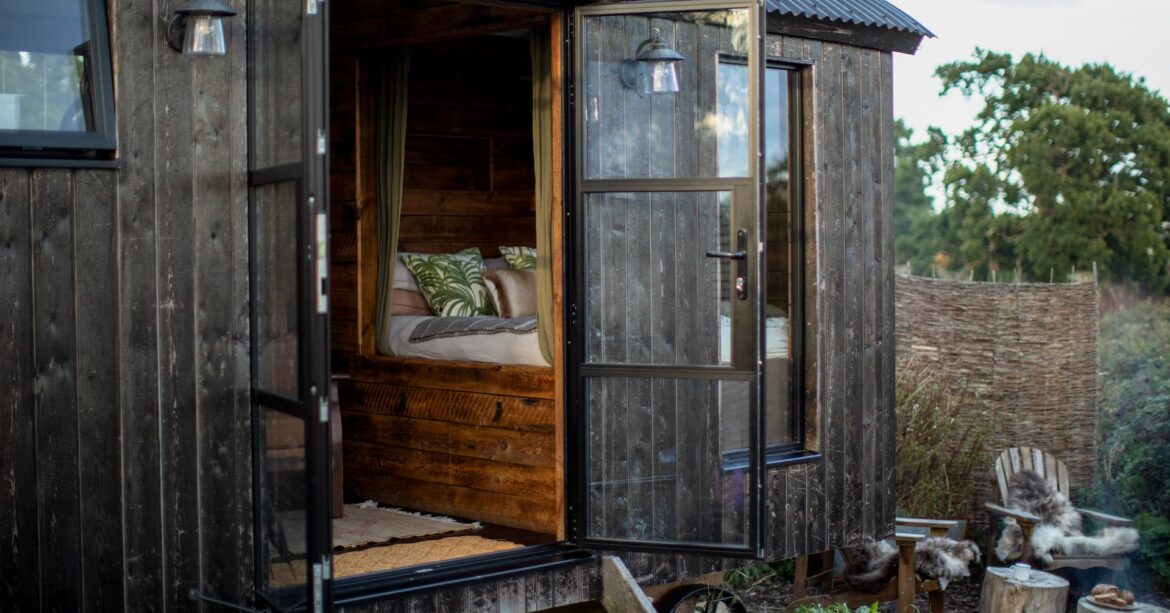Shepherds hut with doors swung open set within a private outside enclosure