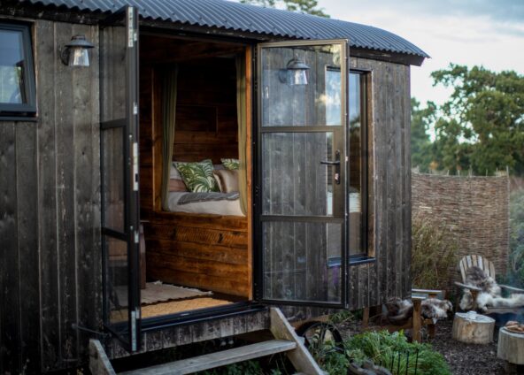 Shepherds hut with doors swung open set within a private outside enclosure