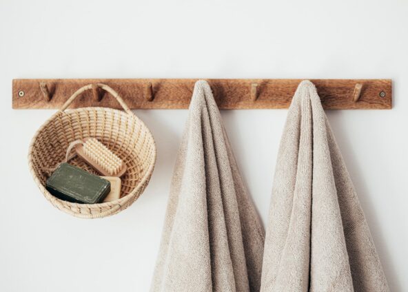 Basket with nail brush and soap in it hanging from a coat hanger alongside two towels